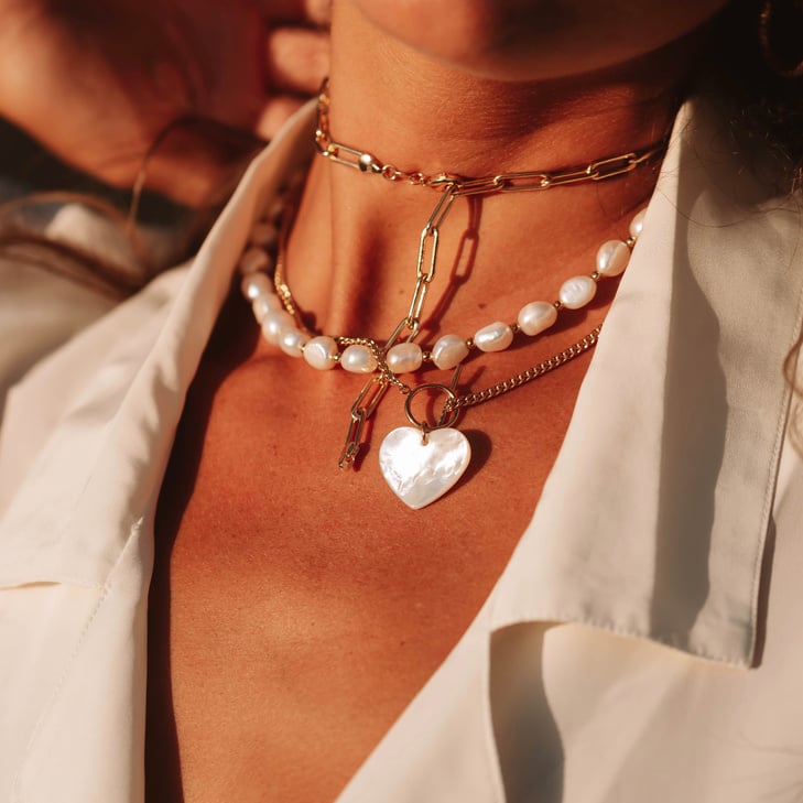 A close up womans neck wearing jewelry in sunset 